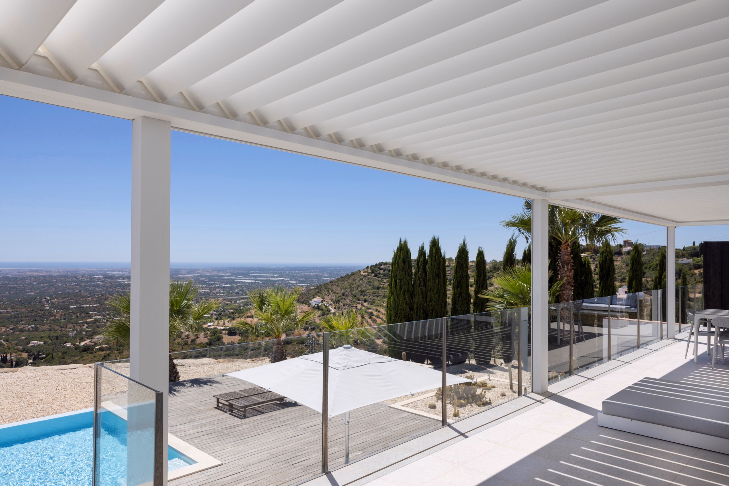 Innenperspektive unter der B200XL-Pergola mit Lamellengeometrie und Glastüren