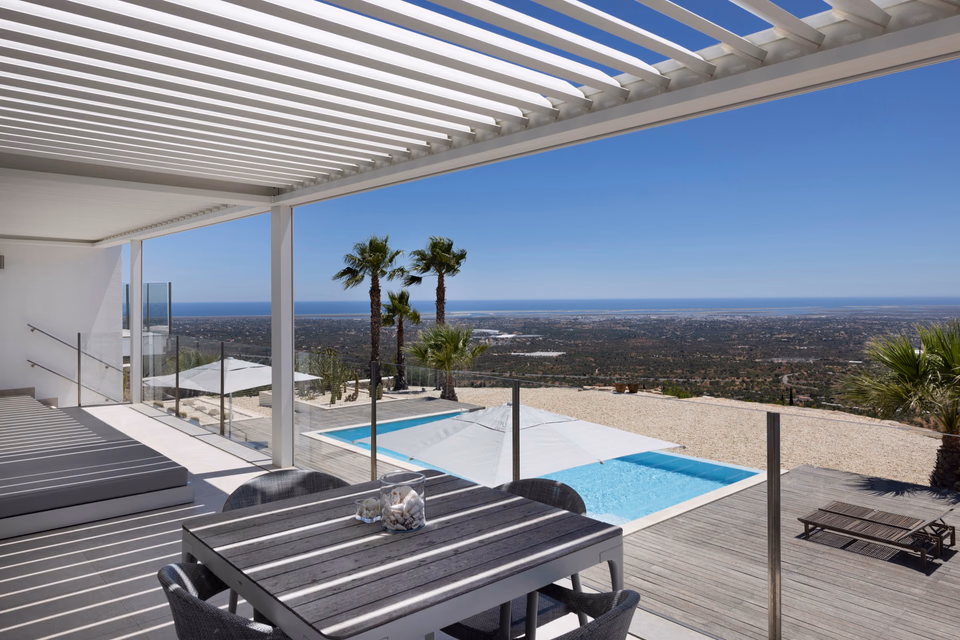 Brustor B200XL Pergola in die Architektur einer modernen Villa mit Pool und Palmengarten integriert