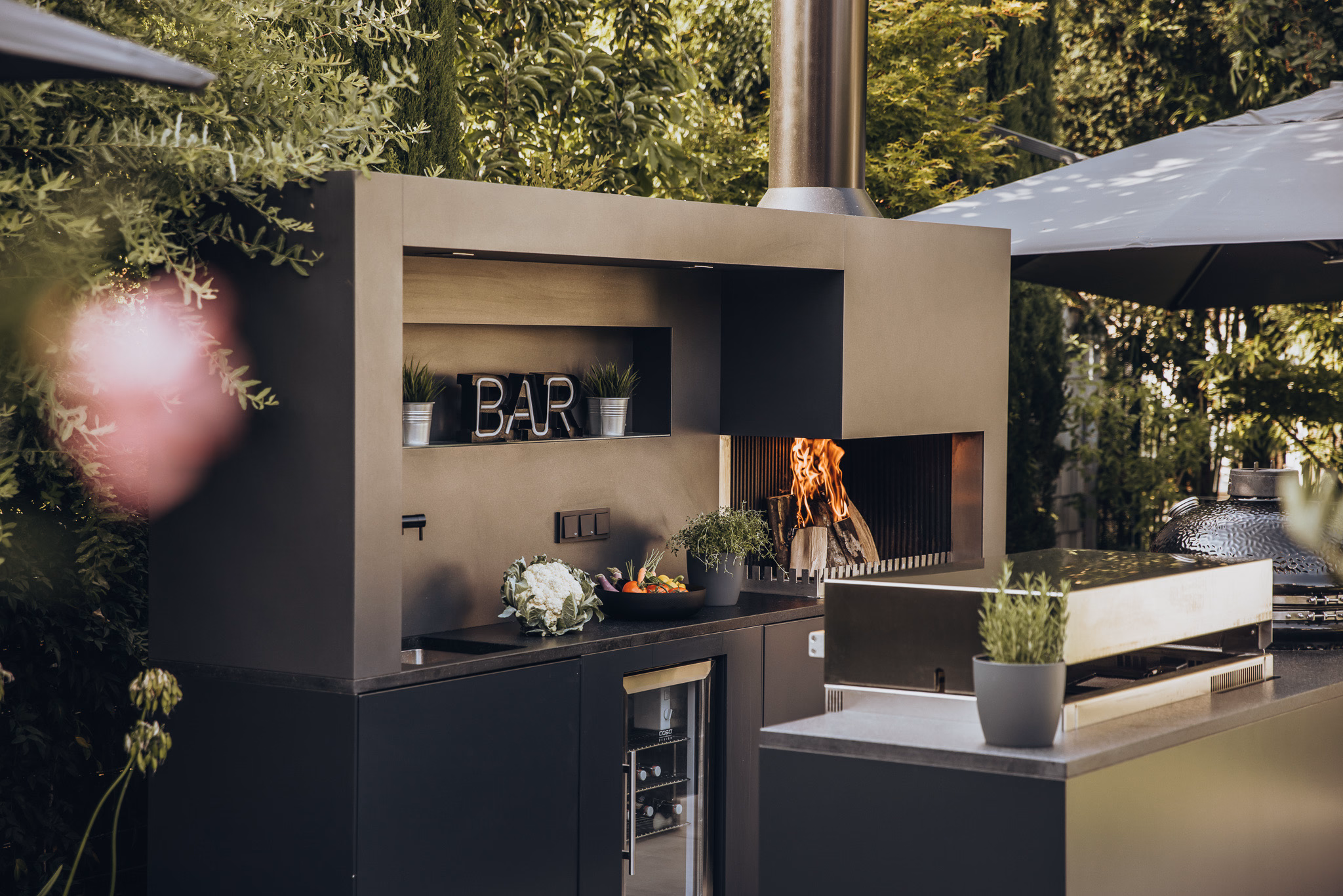 Modular kitchen line with sink and refrigerator under a timber louvre roof