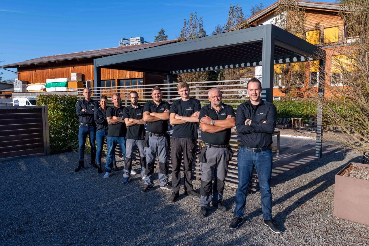 The UNIT Baudienste team in front of a louvered pergola at the company premises